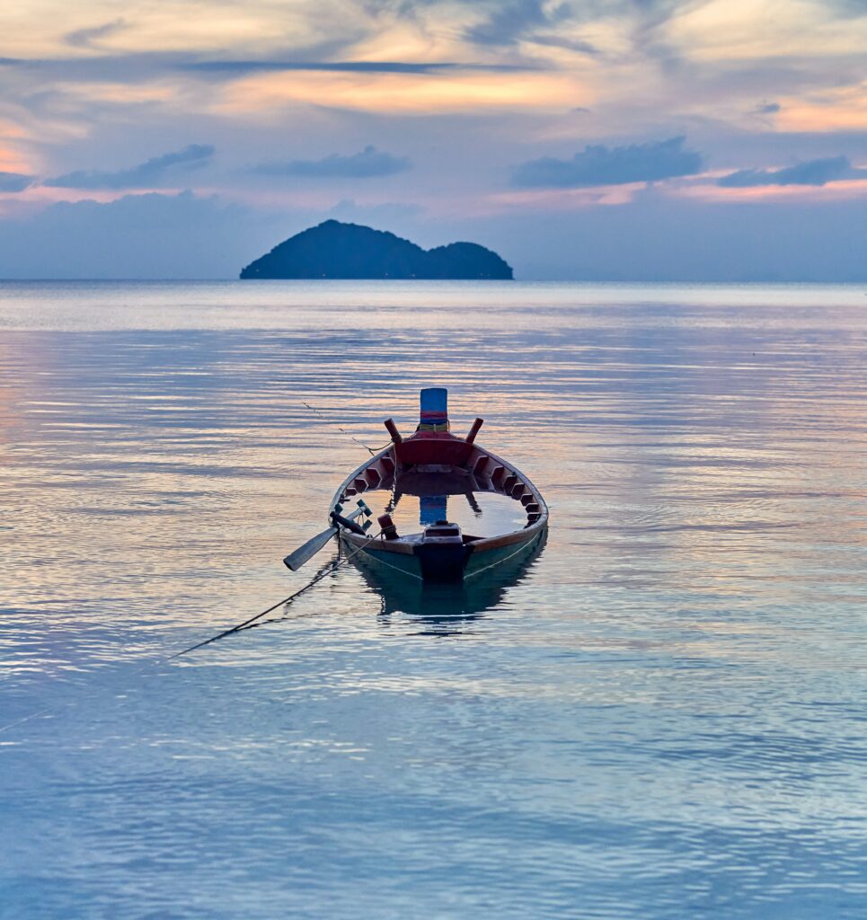 A small fishing boat floating over calm seas. The boat is full of water even as it remains afloat.